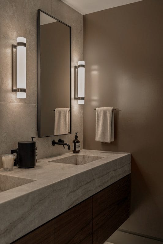 Modern bathroom vanity with double sinks and wall sconces.