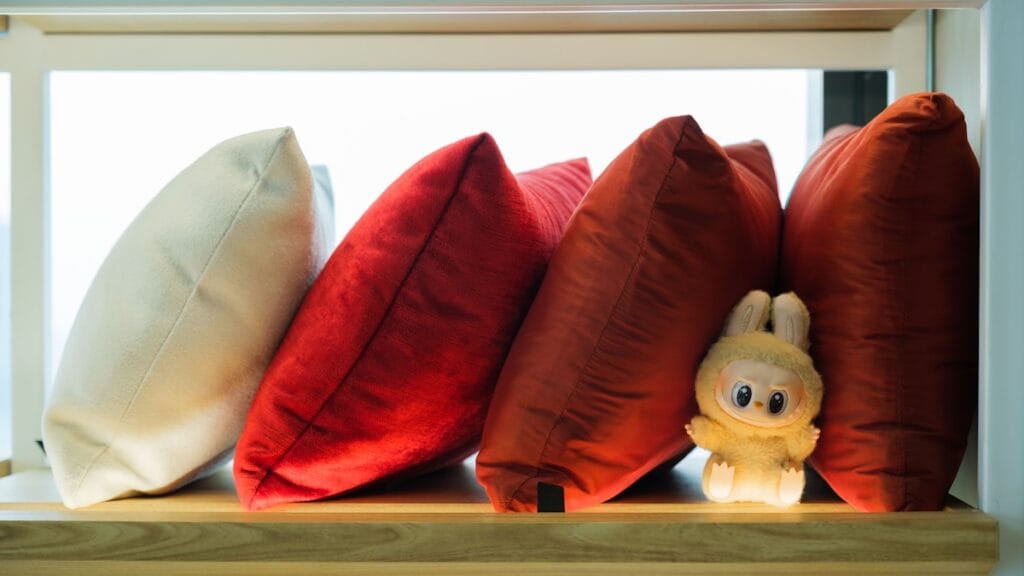 Pillows and a stuffed animal rest on a shelf.