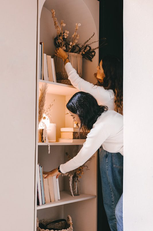 woman in white long sleeve shirt and blue denim jeans standing in front of mirror